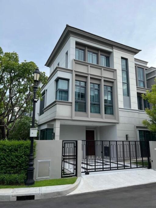 Front view of a modern multi-story house with large windows and a gated driveway