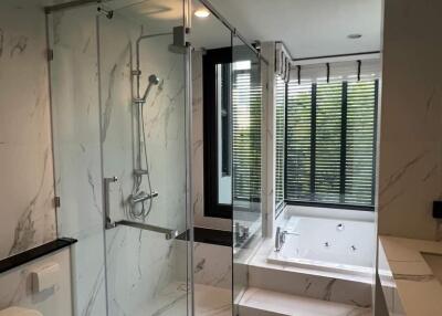 Modern bathroom with glass shower, bathtub, and large window