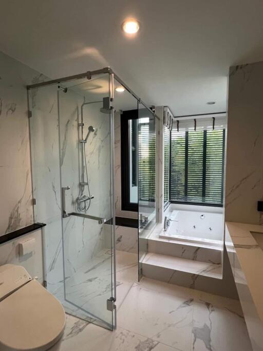 Modern bathroom with glass shower, bathtub, and large window