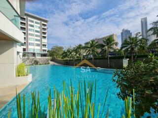 View of a swimming pool area with buildings and palm trees in the background