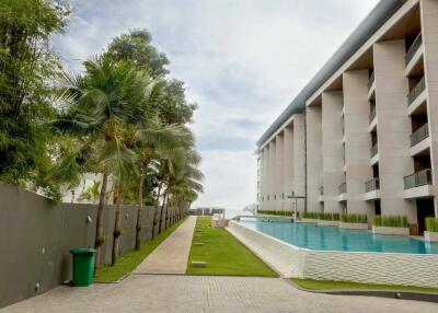 View of the apartment building with a swimming pool and garden area