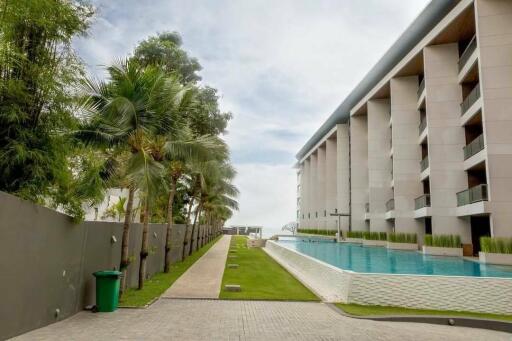 View of the apartment building with a swimming pool and garden area