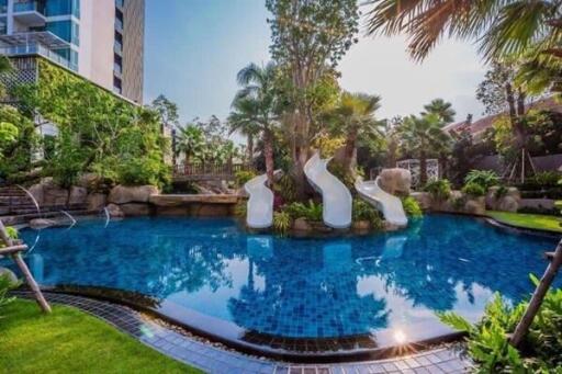 Luxurious outdoor swimming pool with water slides and lush greenery