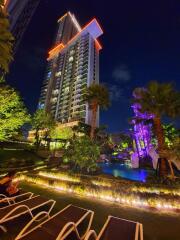 Nighttime view of a tall residential building with illuminated outdoor area and pool