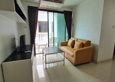 Modern living room with sofa and TV, opening to a balcony