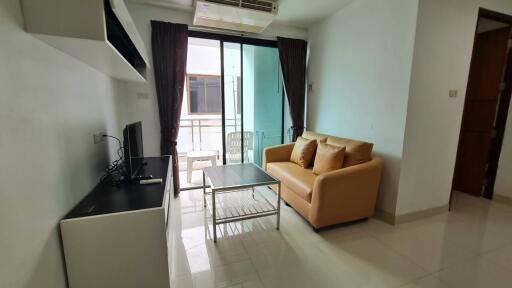 Modern living room with sofa and TV, opening to a balcony