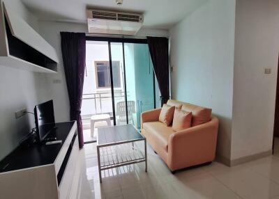 Modern living room with a beige sofa, TV, coffee table, and sliding door to balcony