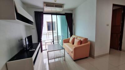 Modern living room with a beige sofa, TV, coffee table, and sliding door to balcony