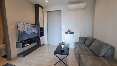 Compact living room with a mounted TV, gray couch, and air conditioner