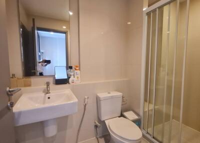 Modern bathroom with a sink, toilet, and shower area.