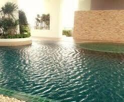 Outdoor swimming pool with stone wall and greenery