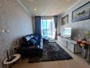 Modern living room with large window, black leather sofa, and TV on white stand.