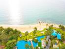 Aerial view of a beachfront property with swimming pools and palm trees