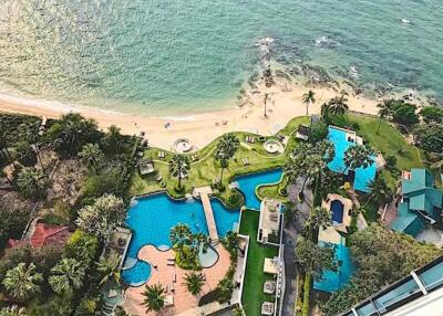 Aerial view of a beachfront property with swimming pools and lush greenery