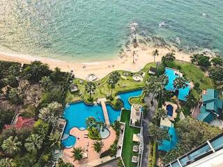 Aerial view of a beachfront property with swimming pools and lush greenery