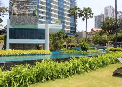 Well-maintained garden and pool area with modern high-rise buildings in the background