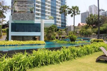 Well-maintained garden and pool area with modern high-rise buildings in the background