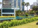 Well-maintained garden and pool area with modern high-rise buildings in the background