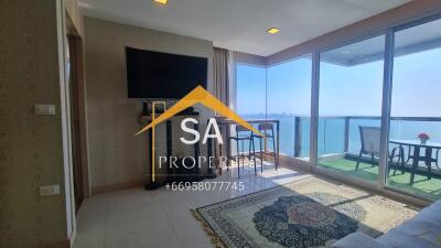 Living room area with large windows, a TV, and an ocean view