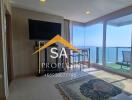 Living room area with large windows, a TV, and an ocean view