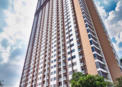 tall residential apartment building with multiple floors and trees at the entrance