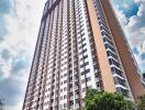 tall residential apartment building with multiple floors and trees at the entrance