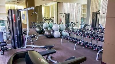 Well-equipped gym with various exercise equipment, mirrors, and exercise balls