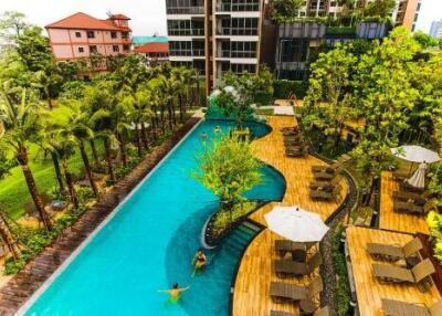 Overview of a pool area in a residential complex with surrounding greenery and lounging areas