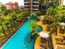 Overview of a pool area in a residential complex with surrounding greenery and lounging areas