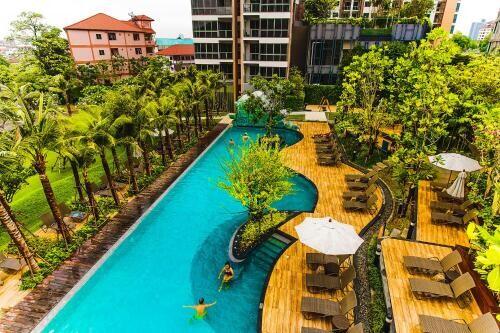 Overview of a pool area in a residential complex with surrounding greenery and lounging areas