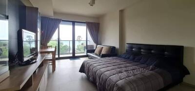 Bedroom with a large window and balcony access, a bed, and a TV