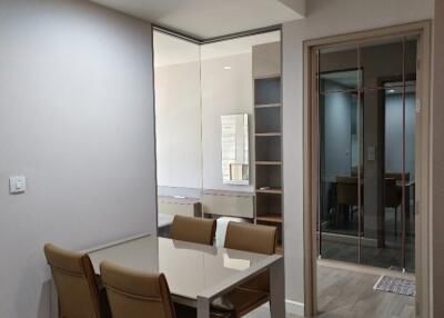 Modern dining area with a table and chairs, featuring a view into an adjacent room with open shelving