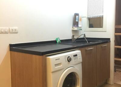 Laundry room with washer and wooden cabinets