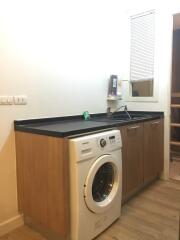 Laundry room with washer and wooden cabinets