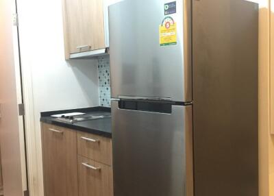 Modern kitchen with stainless steel refrigerator and wooden cabinets