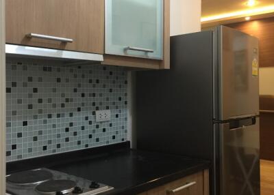 Modern kitchen with wooden cabinets, tile backsplash, and stainless steel fridge