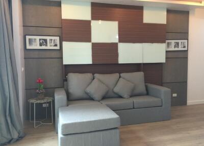 A modern living room with grey sofa and decorative wall panels