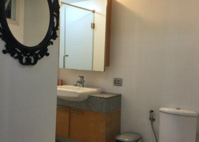 Modern bathroom with a mirror, vanity, toilet, and a laundry basket