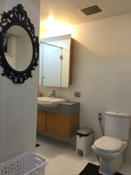 Modern bathroom with a mirror, vanity, toilet, and a laundry basket