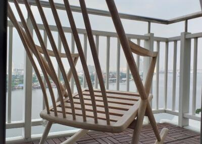 Balcony with a wooden rocking chair overlooking a body of water