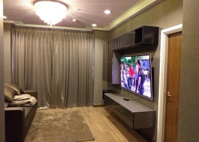 Living room with sofa, wall-mounted TV, and chandelier