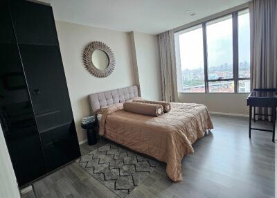 Modern bedroom with large windows, bed, mirror, and wardrobe