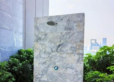 Luxurious outdoor shower area with marble finish and greenery