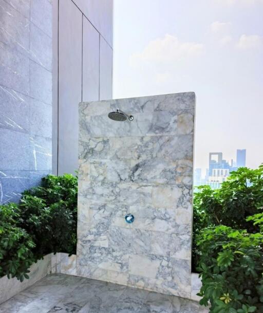 Luxurious outdoor shower area with marble finish and greenery