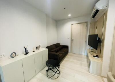 Small modern living room with brown couch, TV, and air conditioning