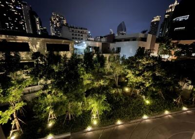 City view of a residential building at night with illuminated greenery