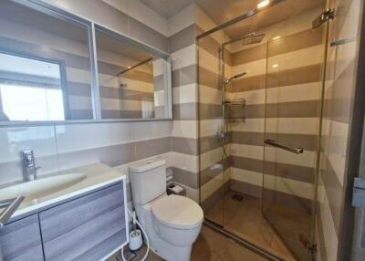 Modern bathroom with glass shower, toilet, and large mirror