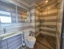 Modern bathroom with glass shower, toilet, and large mirror