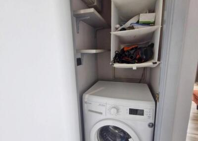 Compact laundry area with a washer and storage shelving