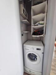 Compact laundry area with a washer and storage shelving